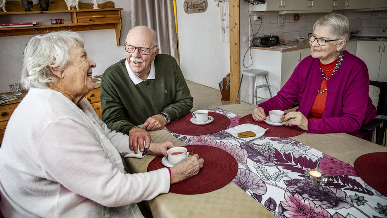 Tre äldre personer samtalar över en kopp kaffe