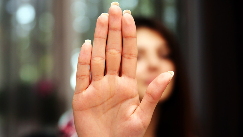 Woman with her hand extended signaling to stop (only her hand is in focus)