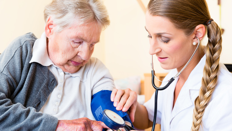 Nurse measuring blood pressure at senior woman patient in retirement home