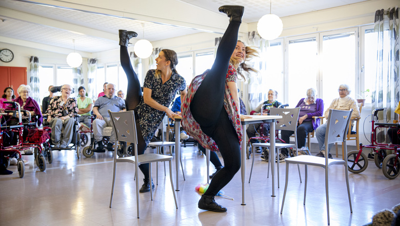 Två kvinnor dansar för ett antal personer på ett äldreboende