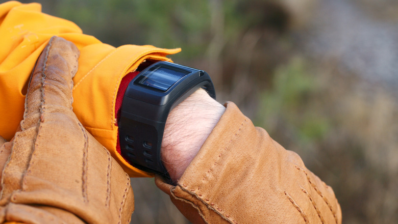 closeup of hands and arm with sportwatch being paused during walk in forest