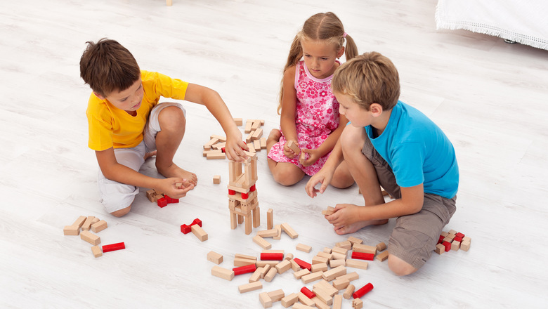 Three kids playing with wooden blocks in their room - top view
