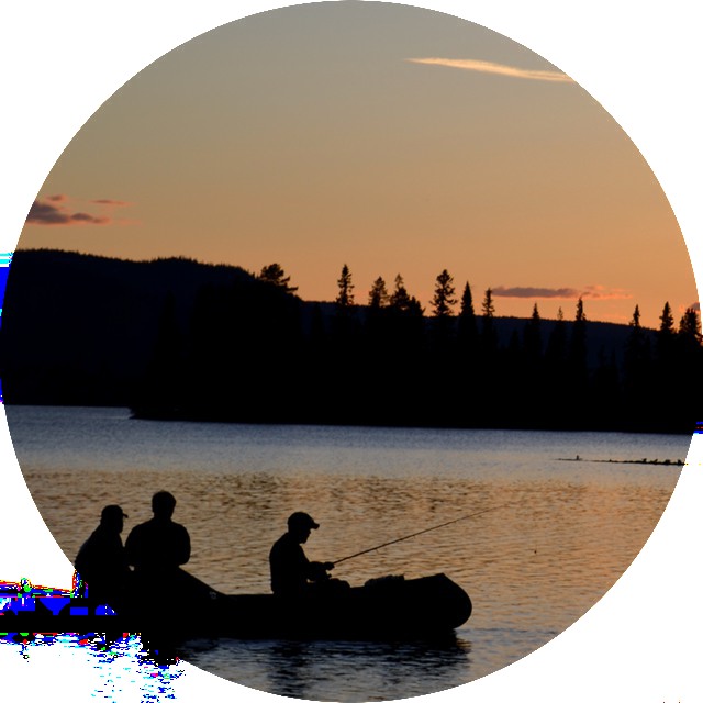 Tre personer fiskar från en kanot i solnedgången.