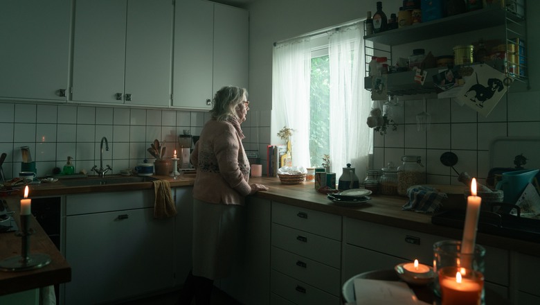 Äldre kvinna står i strömlöst kök. Bilden är vemodig och jag blir lite ledsen av att se på den.