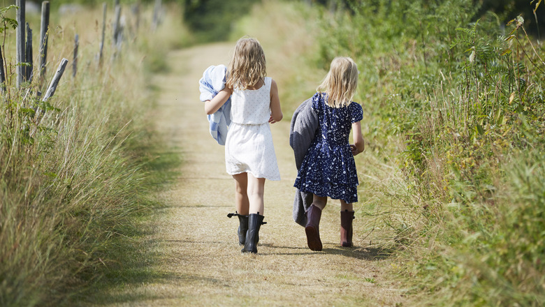 Två flickor som går på en liten stig.