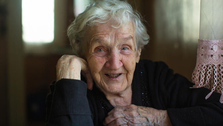Portrait of a happy old woman sitting at a table in the house.