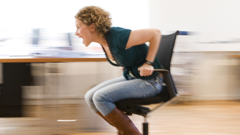 A woman in full speed on an office chair.