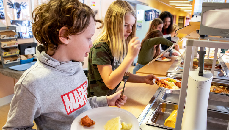 barn tar för sig mat i skolmatsal