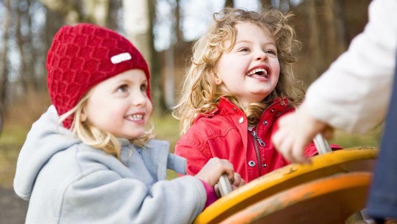 två glada barn leker utomhus i lekpark