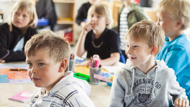 skolbarn i 6-9 års-åldern sitter vid bord i klassrum