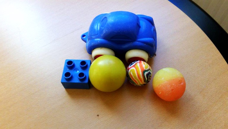 Blå leksaksbil, bollar, studsbollar och en legobit. Hittat på reningsverk.