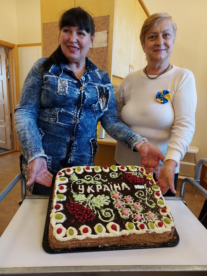 Två kvinnor som visar upp en tårta. 