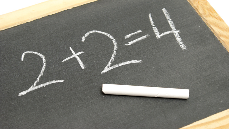 A young student has solved a basic math equation on a chalkboard.