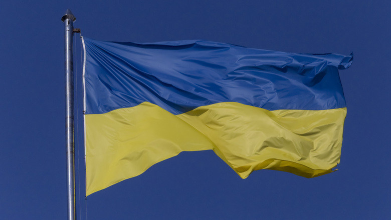 close up of waved Ukrainian flag on flagpole against blue sky