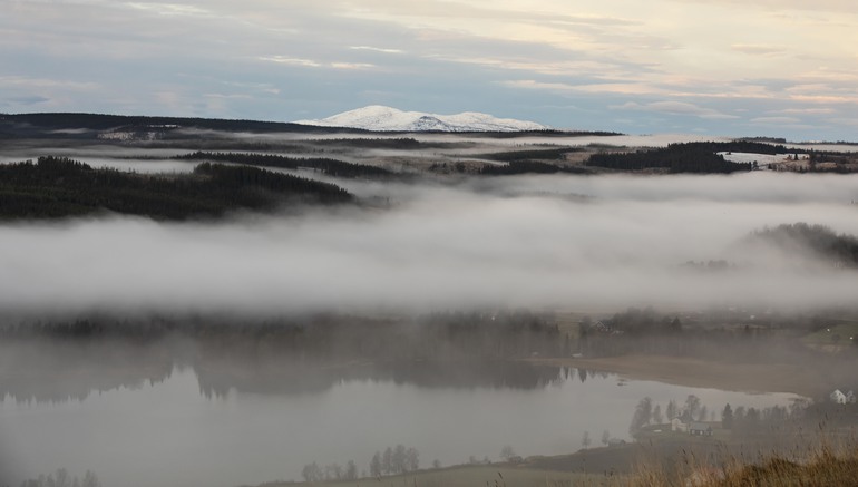 Landskapsbild med dimma och fjäll i bakgrunden