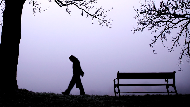 A person walking alone in thick fog.