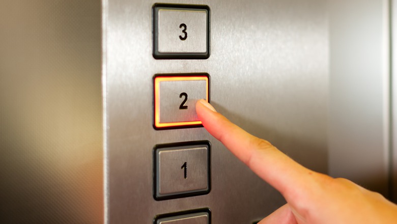 Ett finger trycker på en knapp i en hiss.