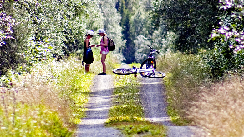 Två flickor på en grusväg med cykel